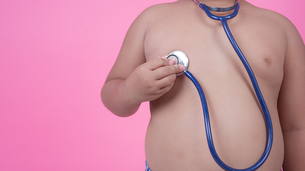 Obese boy who is overweight on a pink background.