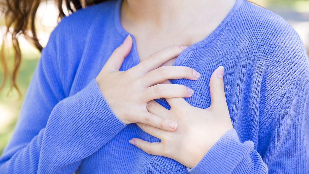 Closeup of young woman touching chest outdoors