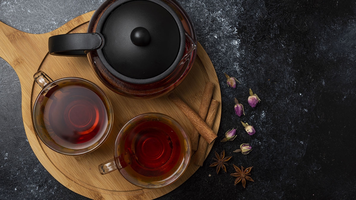 Herbal winter tea in the cups with spices on a wooden board