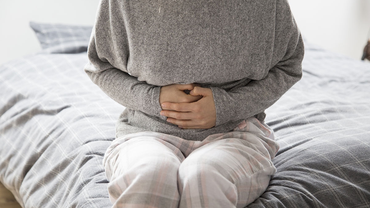 Sick woman with hands on stomach suffering from intense pain