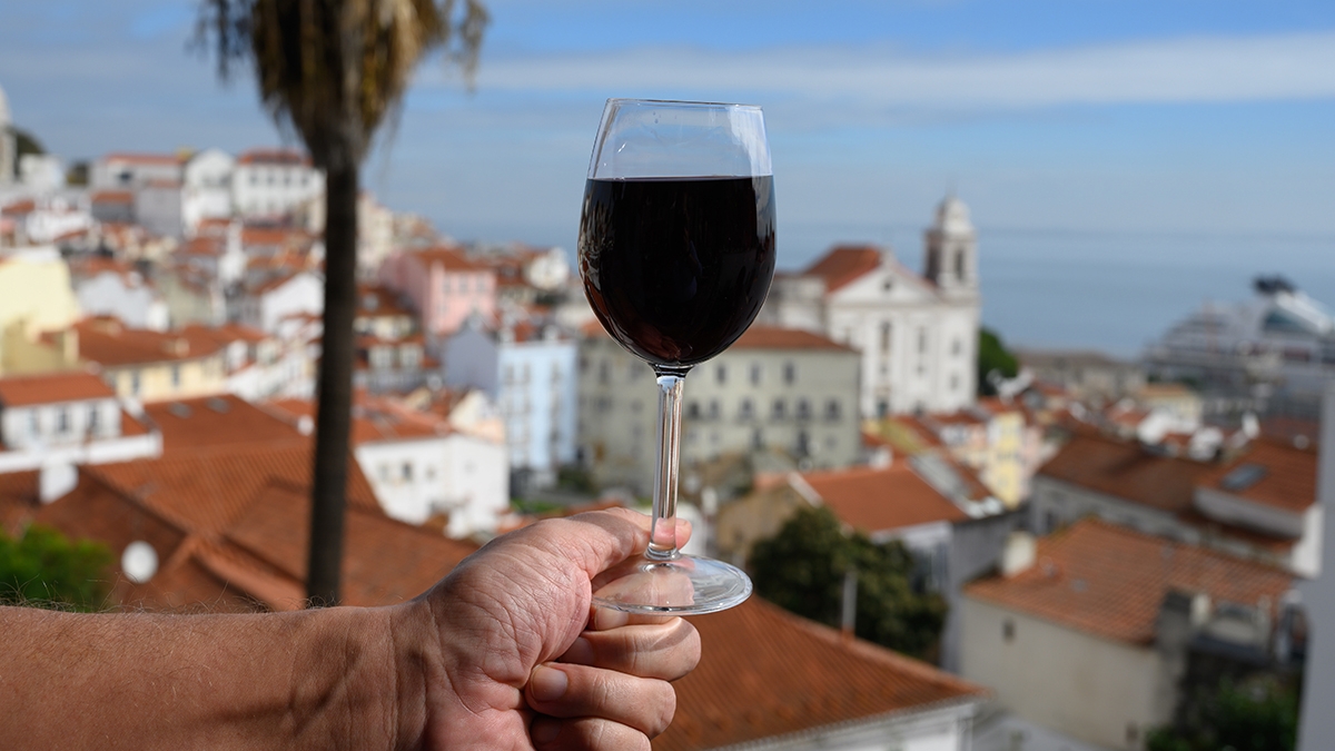 Hand with glass of dry red Portuguese wine in outdoor cafe at vi